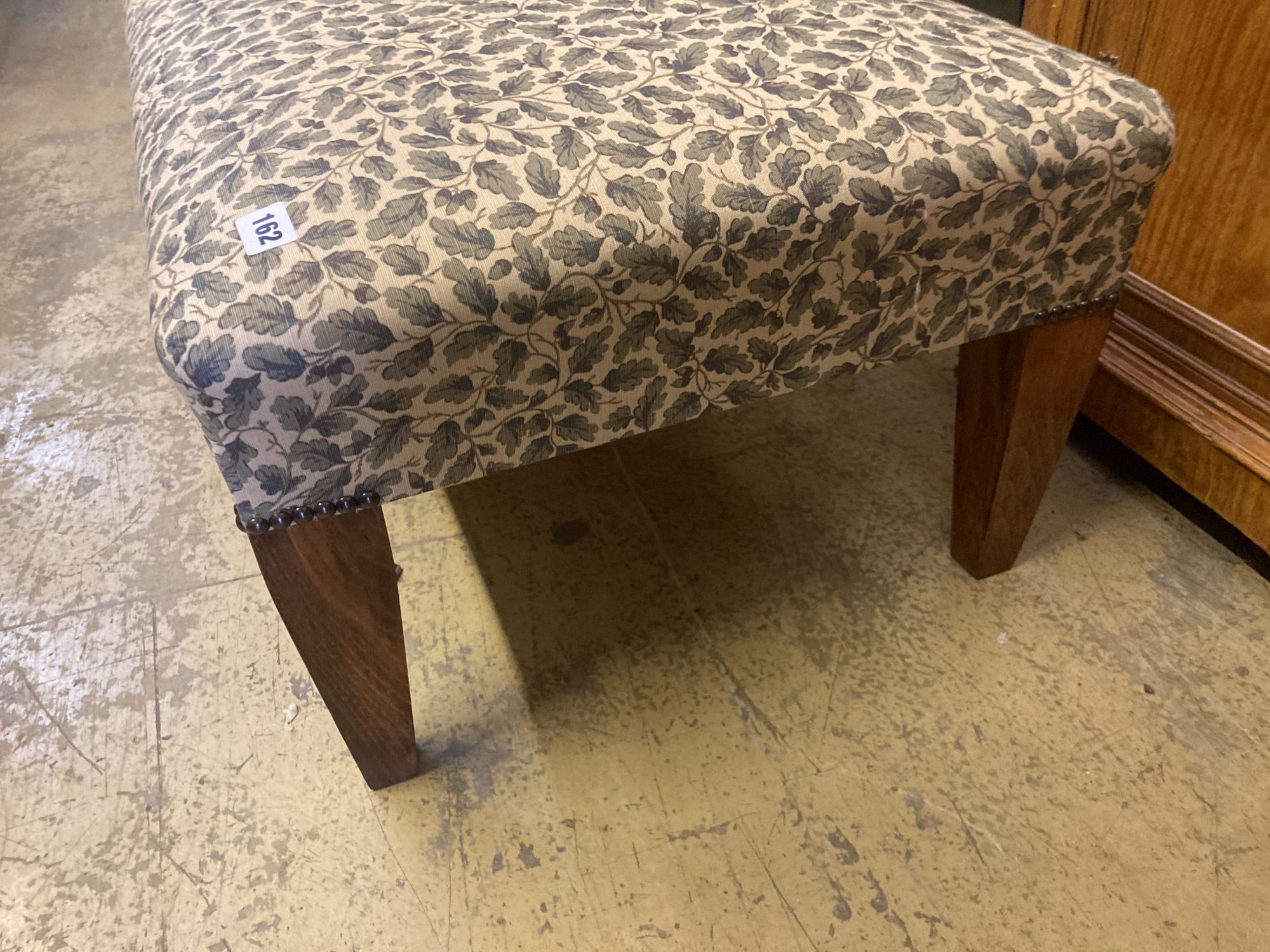 A modern rectangular footstool upholstered in a printed leaf fabric, width 90cm, depth 53cm, height 28cm